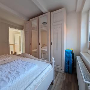 a white bedroom with a bed and a mirror at Fewo "Marienleuchte" in Bannesdorf auf Fehmarn in Fehmarn