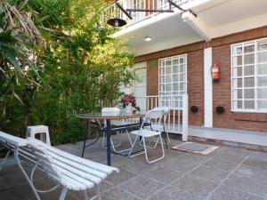 un patio con tavolo, sedie e un edificio di Hostería Teuly a Puerto Madryn