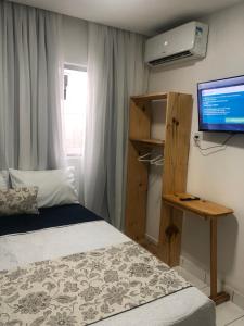 um quarto com uma cama, uma secretária e uma televisão em Pousada LuMar Maragogi em Maragogi