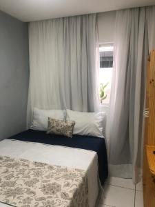 a bedroom with a bed and a window with curtains at Pousada LuMar Maragogi in Maragogi