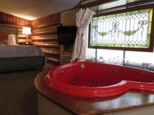 a red bath tub in a bedroom with a stained glass window at Tall Pines Inn in Eureka Springs