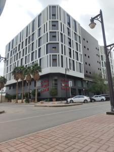 Manazel Al Diafa Serviced Apartments في الرياض: مبنى ابيض كبير على شارع المدينة