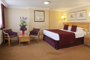 um quarto de hotel com uma cama grande e duas cadeiras em Grange Buckingham Hotel em Londres
