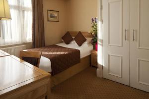 um pequeno quarto de hotel com uma cama e uma janela em Grange Buckingham Hotel em Londres