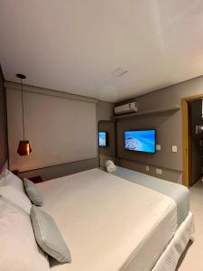 a bedroom with a large bed and a flat screen tv at Elegante quarto e sala Sky Concept 418 Novissímo in Maceió