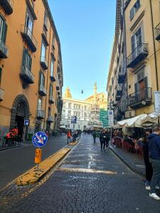 a cobblestone street with buildings and people walking down it at Famme sta cuiete appartamento Napoli centro in Naples