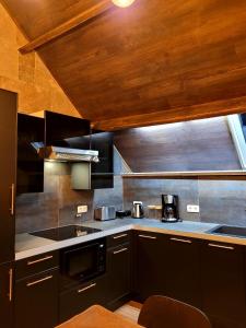 una cucina con elettrodomestici neri e soffitto in legno di Chez Claude appartement cozy climatisé pour 4 personnes tout confort a Ath