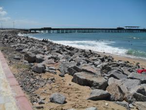 a rocky beach with a pier in the water at Suites Vila de Iracema in Fortaleza