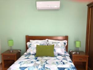 ein Schlafzimmer mit einem Bett mit einem grünen Kissen darauf in der Unterkunft Casa da Forja in Aldeia das Dez