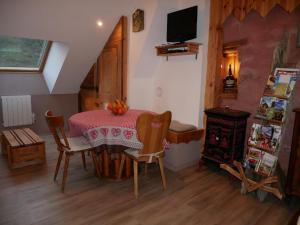 une salle à manger avec une table, des chaises et une télévision dans l'établissement Gîte du Durrenbach, à Lautenbach