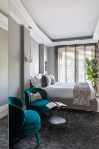a bedroom with a bed and a blue chair at NAMAN HOTELLERIE - Spagna in Rome