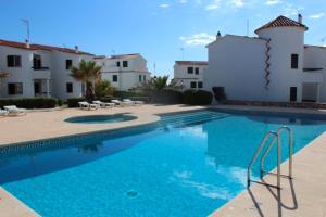 a swimming pool in front of a building at Apartamentos Mar a mar in Cala en Forcat