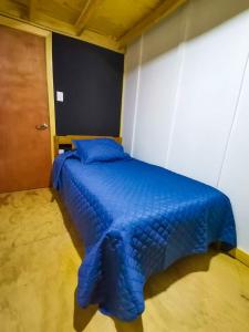 een bed met een blauw dekbed in een kamer bij Cabaña Traitraico Melipeuco in Melipeuco