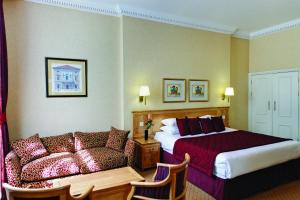 um quarto de hotel com uma cama e um sofá em Grange Buckingham Hotel em Londres