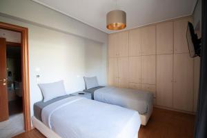 Cozy & Relaxing Apartments-Agia Paraskevi في أثينا: غرفة نوم بسريرين وتلفزيون فيها