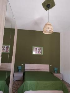 Habitación verde con cama y lámpara de araña. en NA ZA ROSA, en Porto Empedocle