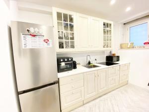 uma cozinha com armários brancos e um frigorífico em Suite23_Ortigia em Siracusa