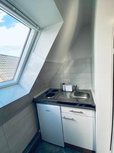 Elle comprend une petite cuisine avec un évier et une fenêtre. dans l'établissement Dümmer Perle Apartments, à Hüde