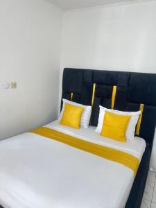 a bedroom with a bed with yellow pillows at Chambre Moderne (Kotto) in Douala