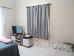 a bedroom with a bed and a desk with a television at Dom Gabriel 4 in Campos dos Goytacazes