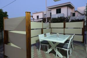 einen Tisch und Stühle auf einer Terrasse mit einem Zaun in der Unterkunft Cannotta Beach - Salina in Terme Vigliatore