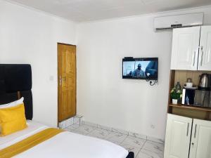 a bedroom with a bed and a tv on the wall at Chambre Moderne (Kotto) in Douala