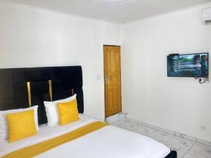a bedroom with a bed with yellow pillows and a tv at Chambre Moderne (Kotto) in Douala