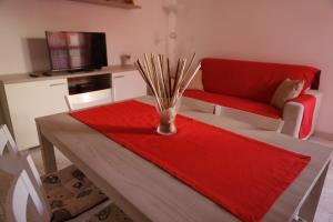 a living room with a table and a red couch at Cannotta Beach - Alicudi in Terme Vigliatore