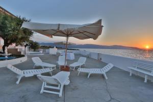 a patio with chairs and an umbrella and the ocean at Cannotta Beach - Alicudi in Terme Vigliatore