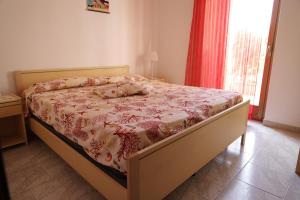 a bedroom with a bed with a floral bedspread and a window at Cannotta Beach - Alicudi in Terme Vigliatore