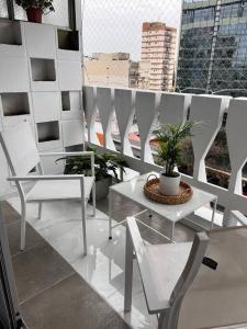 balcón con sillas blancas, mesa y plantas en departamento moderno en Belgrano en Buenos Aires