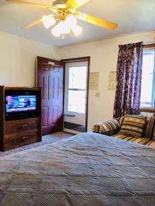 een slaapkamer met een bed en een flatscreen-tv bij Black Hills Motel at Quail's Crossing in Hill City