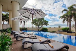 una fila de tumbonas con sombrillas junto a una piscina en The Costa Central and Luxury 2 bedrooms, en Nha Trang
