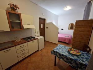 a small kitchen with a table and a room with a bed at Monolocali in centro paese in Lampedusa