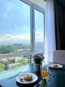 una mesa con dos platos de comida y una ventana en MEDINAHOTELKZ, # 63, вид на горы, 15 мин пешком до арбата, HALAL, en Almaty