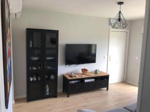 uma sala de estar com televisão e um armário preto em Apartamento frente a la playa con vistas al mar en Barro, Llanes em Barro de Llanes
