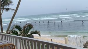 a balcony view of the beach with surfers in the ocean at Lihinya Beach Villa Ahangama in Ahangama