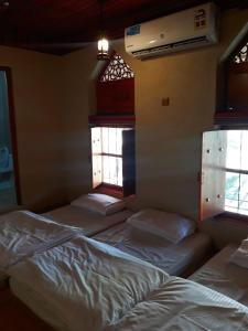 een kamer met 3 bedden en 2 ramen bij Balad Sayt Heritage Inn in Bilād Sayt