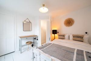een witte slaapkamer met een groot bed en een bureau bij Fisherman's Cottage, Whitstable in Whitstable