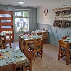 uma sala de jantar com mesas e cadeiras de madeira em Hostal Mahuida em Pucón