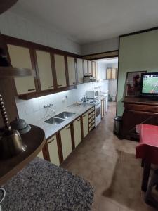 cocina con fregadero y TV de pantalla plana. en PISO ÚNICO ZONA SHOPPING CATEDRAL Mar del Plata - NO SE ACEPTAN GRUPOS DE JOVENES en Mar del Plata