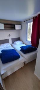 1 Schlafzimmer mit 2 Betten mit blauen Kissen und einem Fenster in der Unterkunft Chalet et mobil homes dans la montagne au Camping les Sapins in Camurac