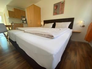 a large white bed in a room with wooden floors at Fleiner Gästehaus in Flein