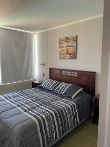 une chambre avec un grand lit et une couverture à rayures dans l'établissement Dpto tipo Resort, à Viña del Mar