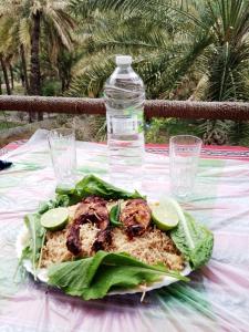 een bord eten op een tafel met een fles water bij Mahalli Balad Sayt Heritage Inn in Bilād Sayt