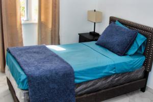 sypialnia z łóżkiem z niebieską pościelą i lampką w obiekcie Sea-Renity w mieście Oyster Pond