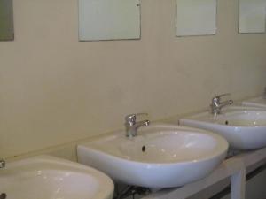 Tres lavabos en un baño con tres grifos en Sóstói Lovaskemping és Turistaház en Nyíregyháza