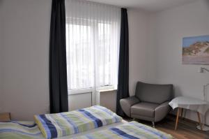 a bedroom with a bed and a chair and a window at Ferienhaus Nordstrand Whg 2 in Baltrum