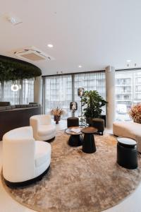 a lobby with white chairs and tables on a rug at The CORNR Hotel in Nieuwpoort