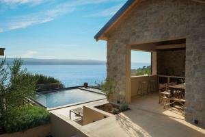 a villa with a pool and a view of the ocean at Luxauthentic villa with heated pool SALT STONE - sauna, jacuzzi, gym, outdoor kitchen with bbq in Mimice